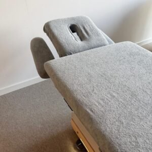 Grijze massagetafel met hoofdsteun in rustige ruimte