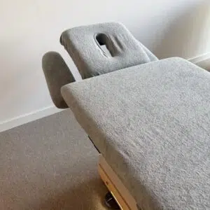 Grijze massagetafel met hoofdsteun in rustige ruimte